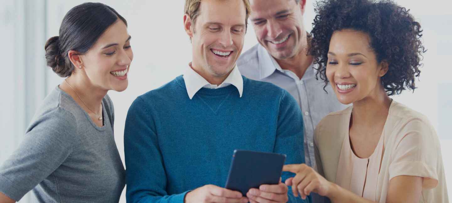 4 People smiling while looking at a phone